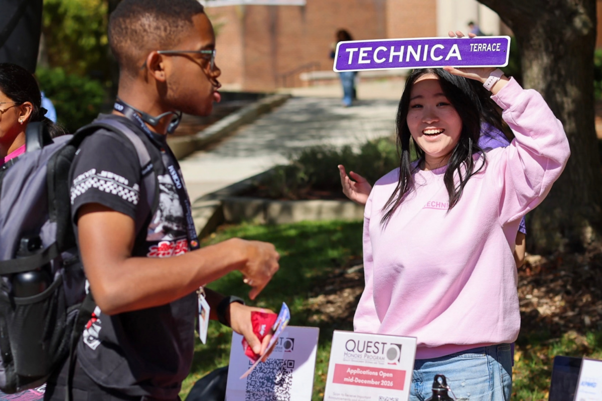 Student at the Technica table holding up a Technica sign