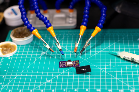 Alligator clips pointing to a microprocessor on a cutting mat